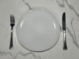 A white plate with a fork and knife on either side.